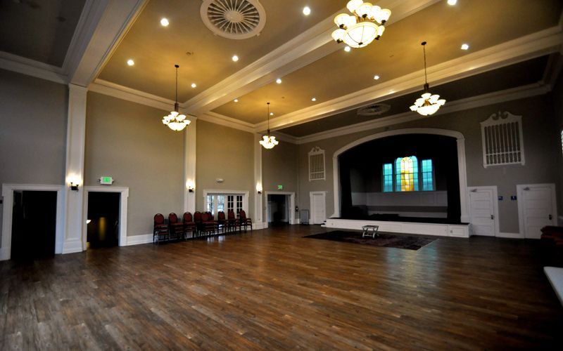 A large empty room with wooden floors and a stage.