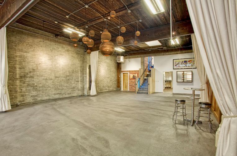 A large empty room with a brick wall and a staircase.