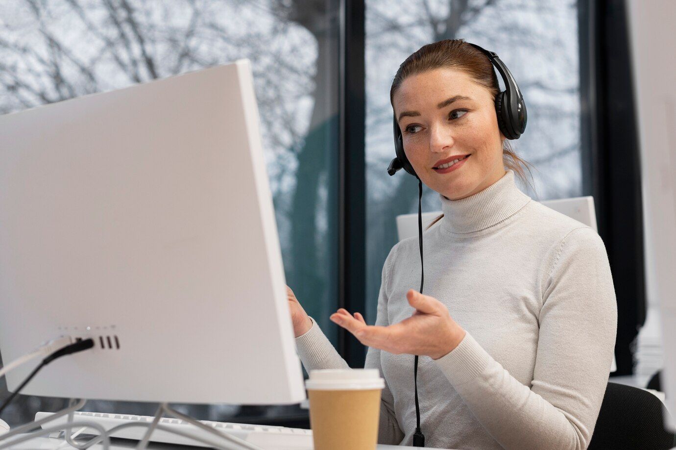A woman wearing headphones is sitting in front of a computer.