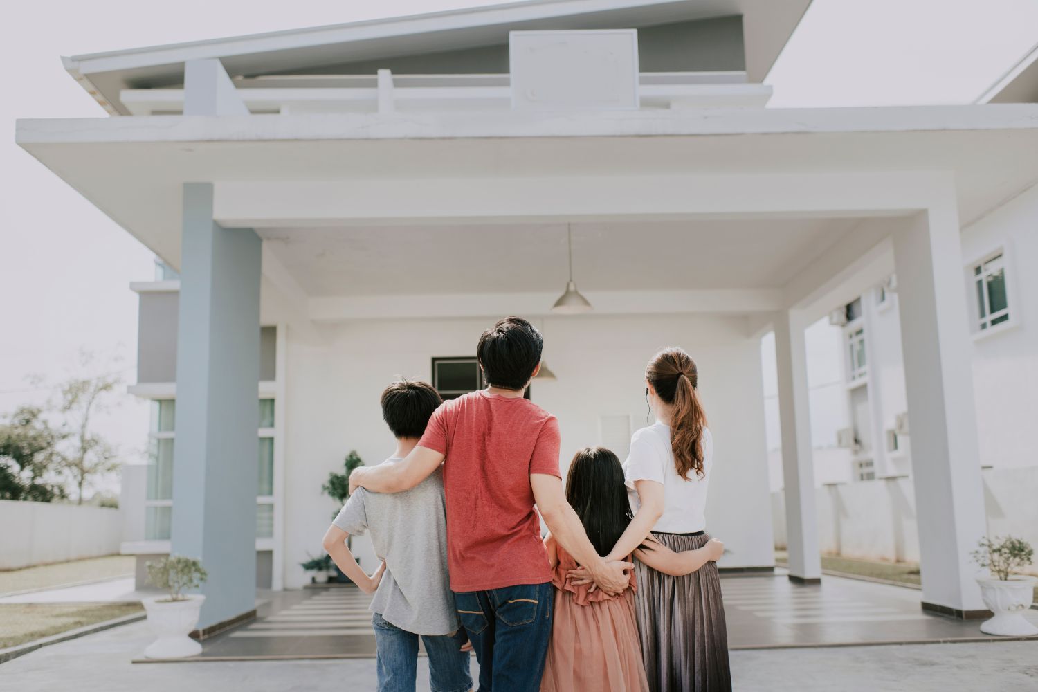 Family standing in front of their modern house, looking up.