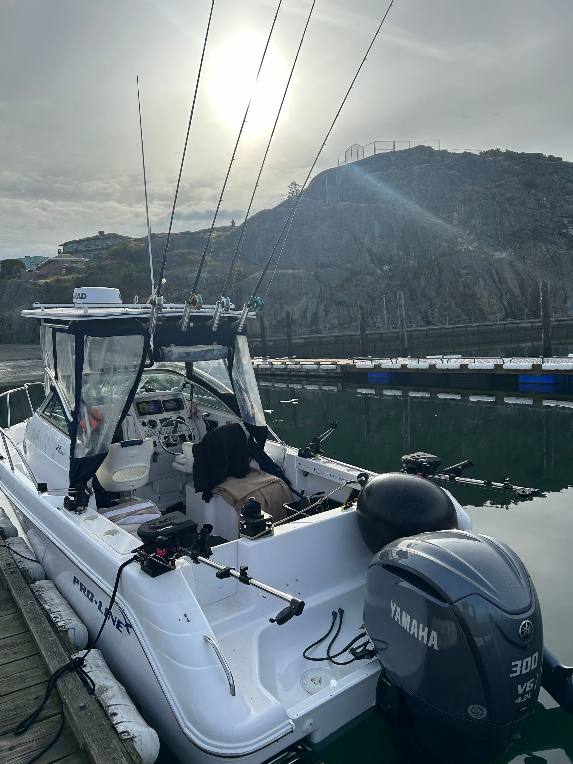 A white boat is docked in a harbor with mountains in the background.