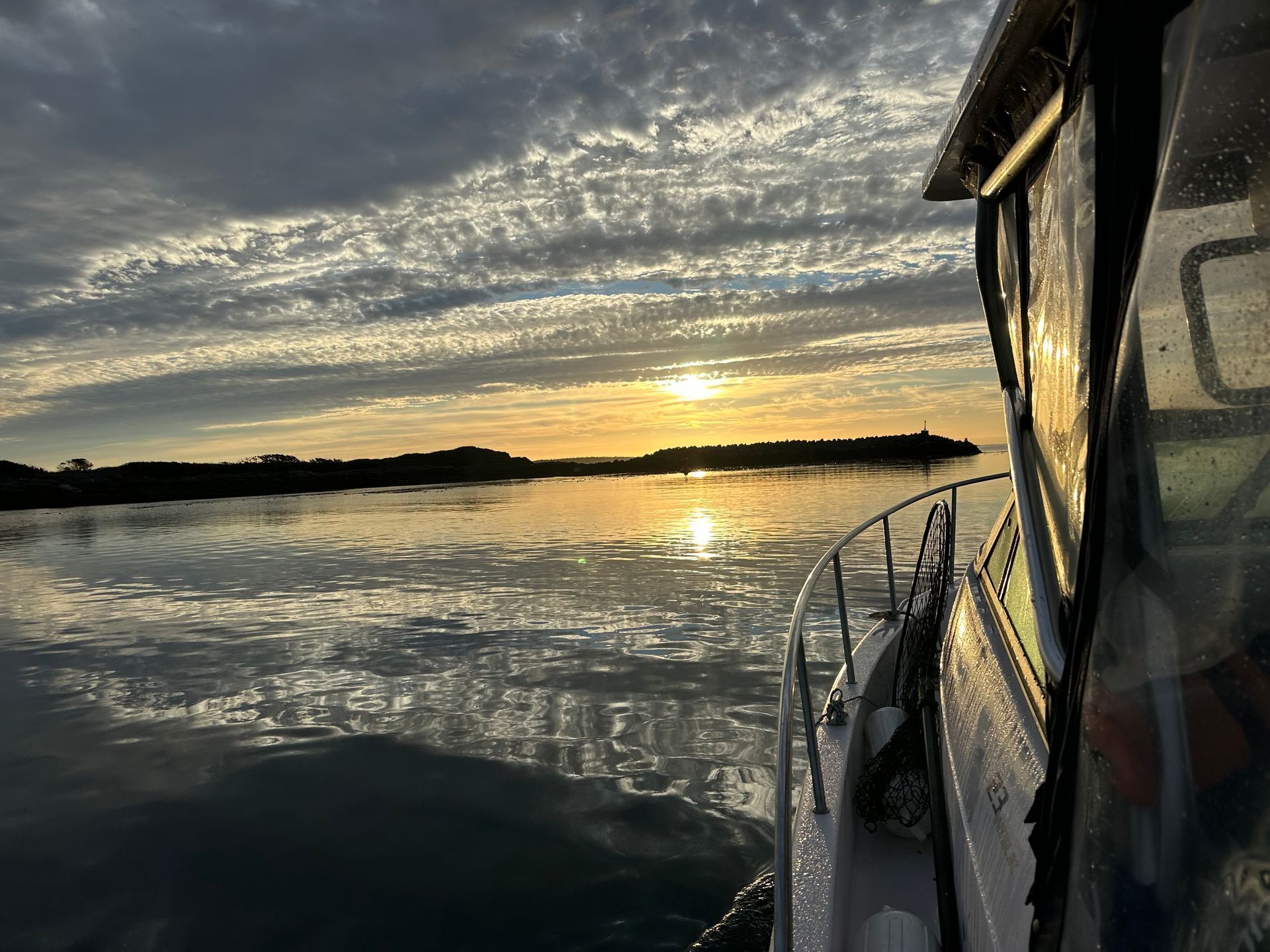 A boat is floating on top of a body of water at sunset.