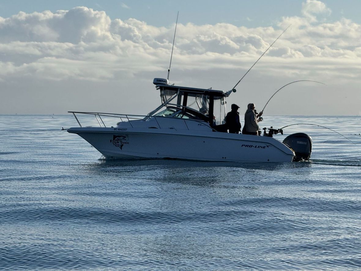 Boat with two people fishing on calm water.