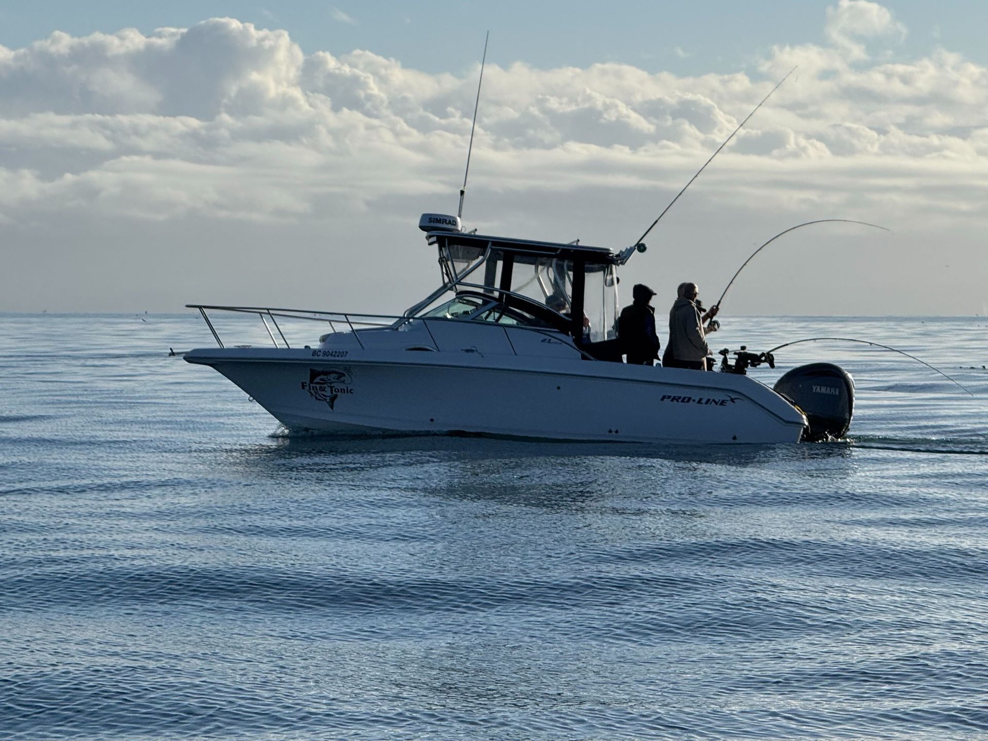 Two men are fishing on a boat in the ocean.