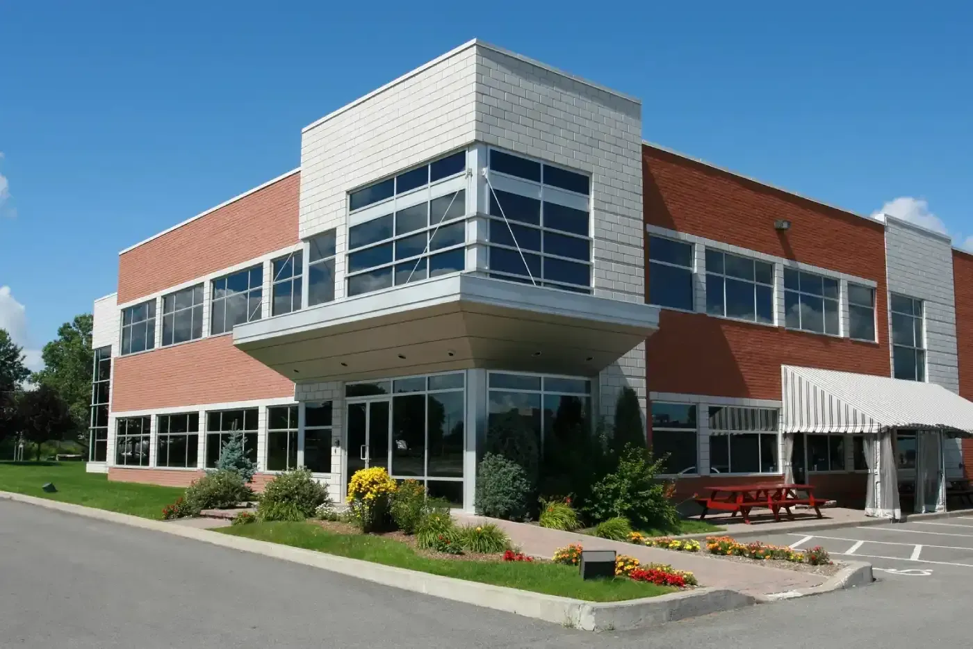Modern brick-and-glass office building with landscaped entrance and awning