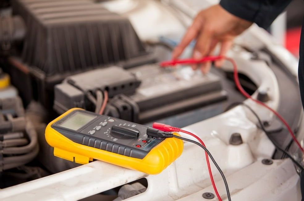 A Person Is Using A Multimeter To Test A Car Battery — Goulburn Automotive Centre In Goulburn, NSW