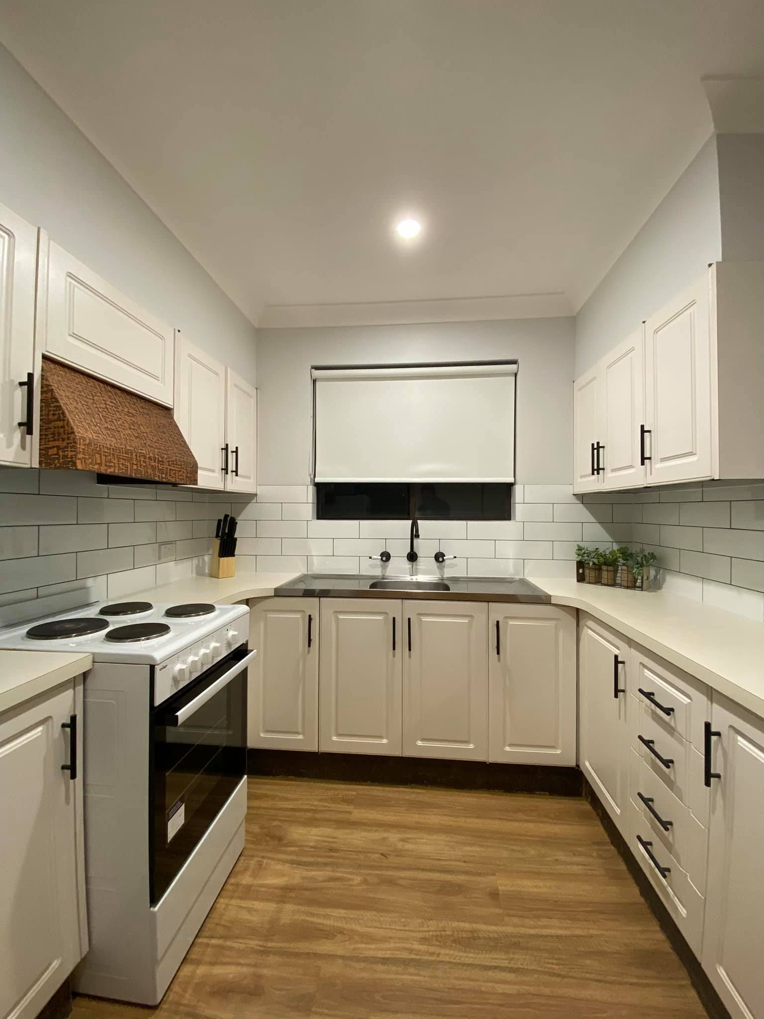 Bright White Galley Kitchen with White Cabinets and A Window with Blinds — Tamworth Blinds & Awnings in Walcha, NSW