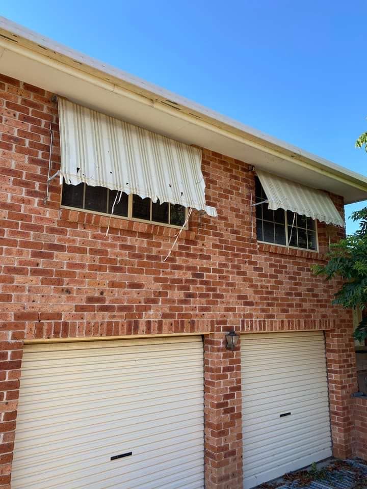 Brick Apartment Building with White Garage Doors and Striped Awnings — Tamworth Blinds & Awnings in Narrabri, NSW
