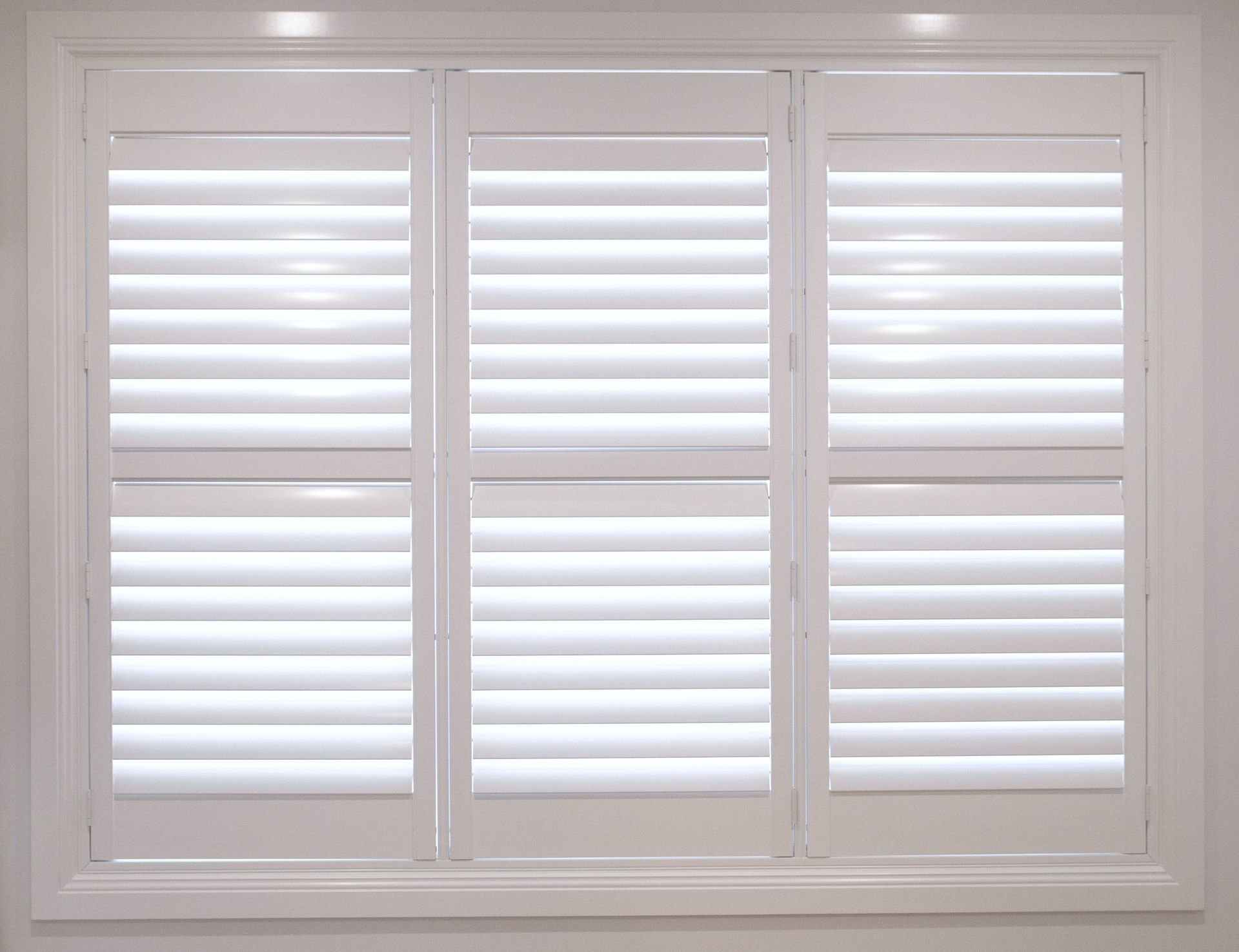 White plantation shutters on a window with multiple rectangular panes