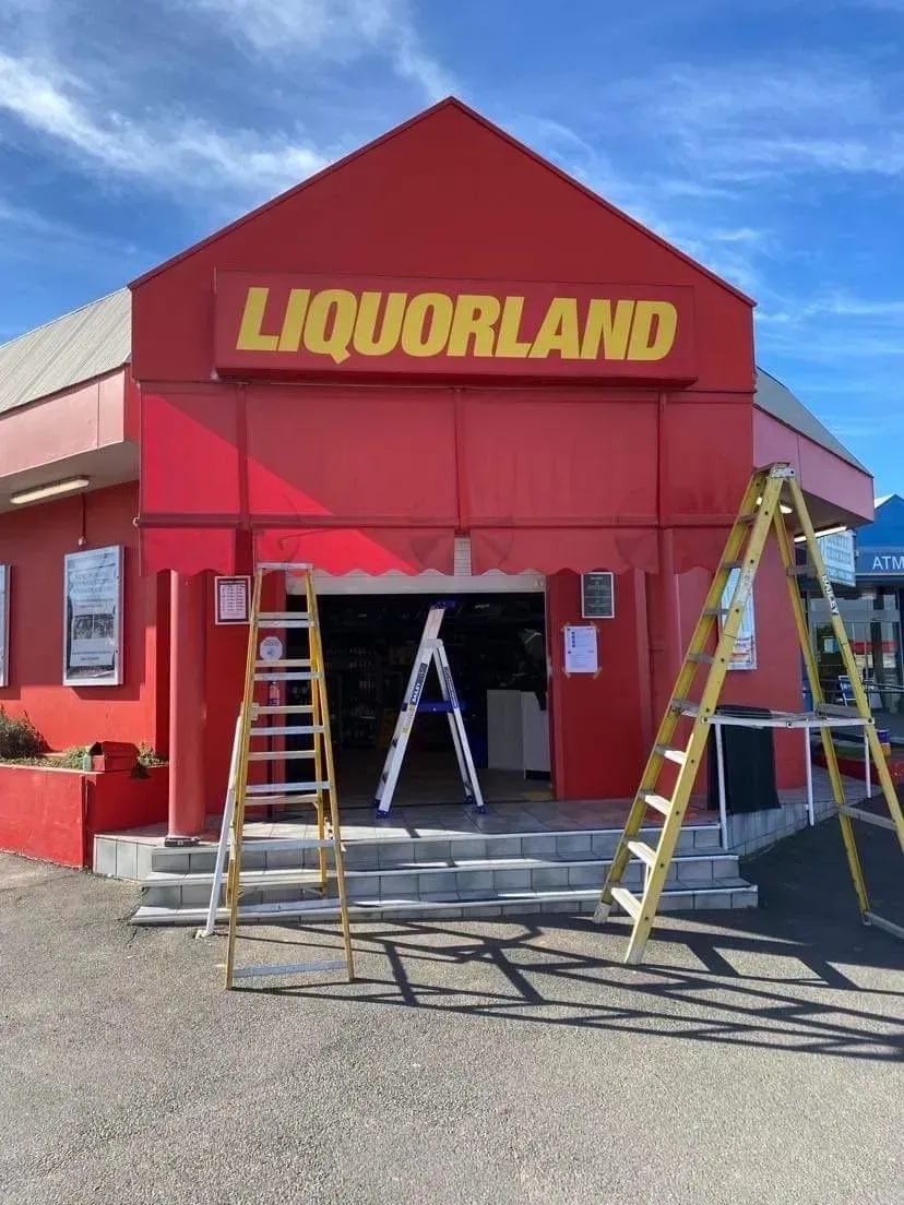 Liquorland Storefront with Red Facade and Ladders Outside — Tamworth Blinds & Awnings in Tamworth, NSW