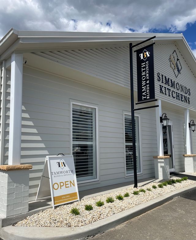 Exterior of Simon Kitchens storefront with white siding, porch columns, and an open sign under cloudy skies
