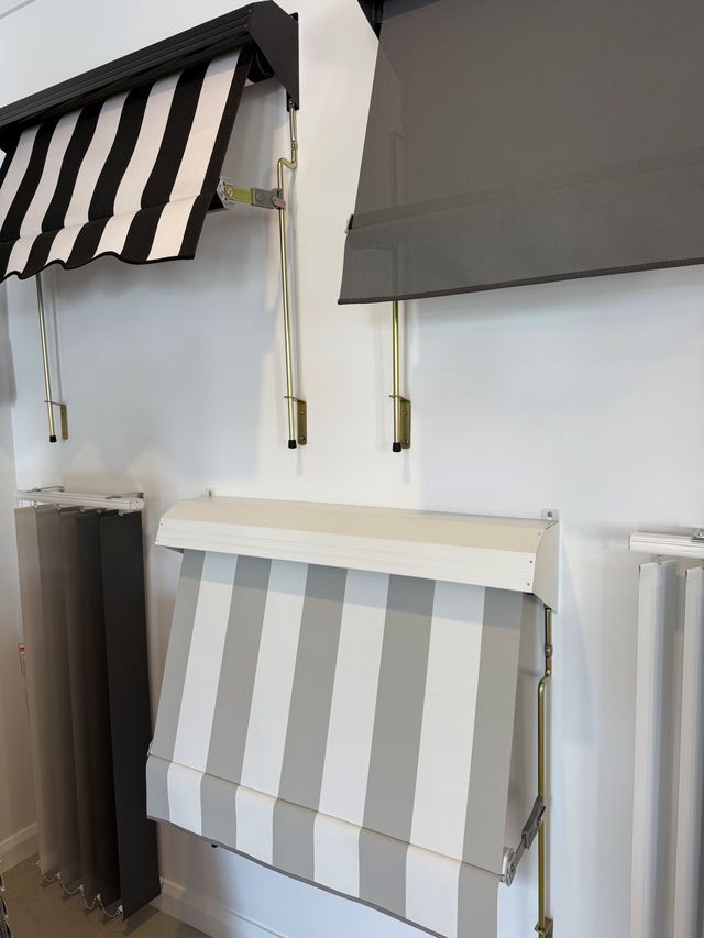 Striped and solid awnings displayed on a white wall indoors