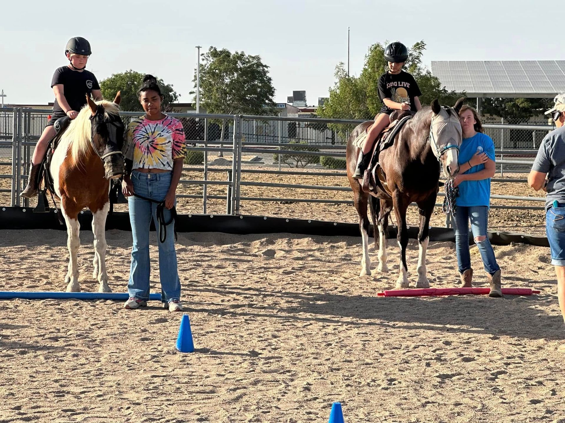 A group of children are riding horses in a dirt arena.