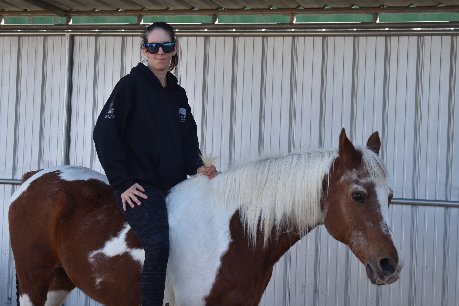 A woman is sitting on the back of a brown and white horse.