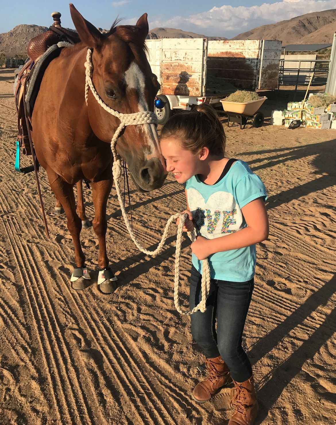 A little girl is riding a pony in a dirt field.