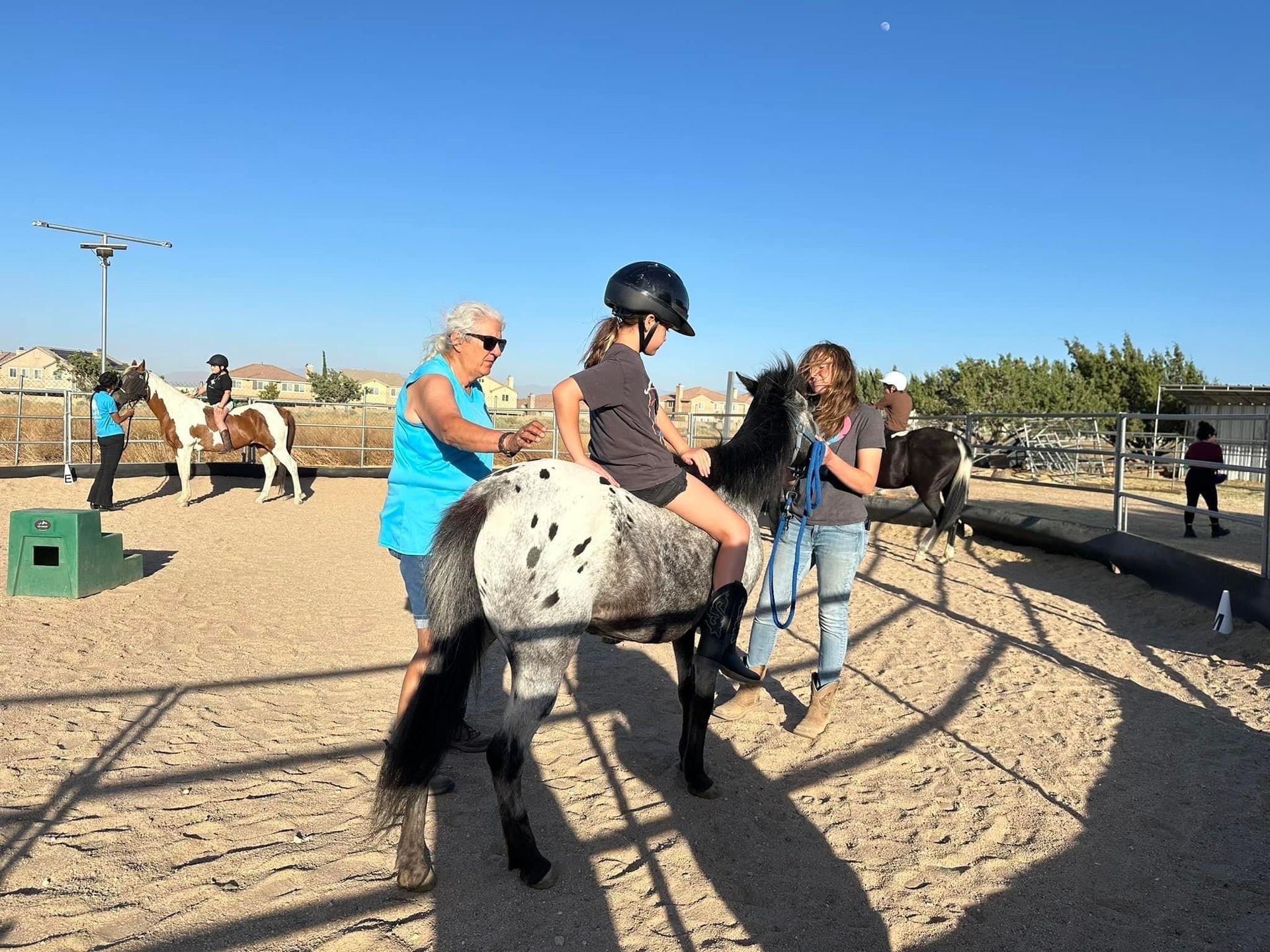 A little girl is riding a pony in a dirt field.