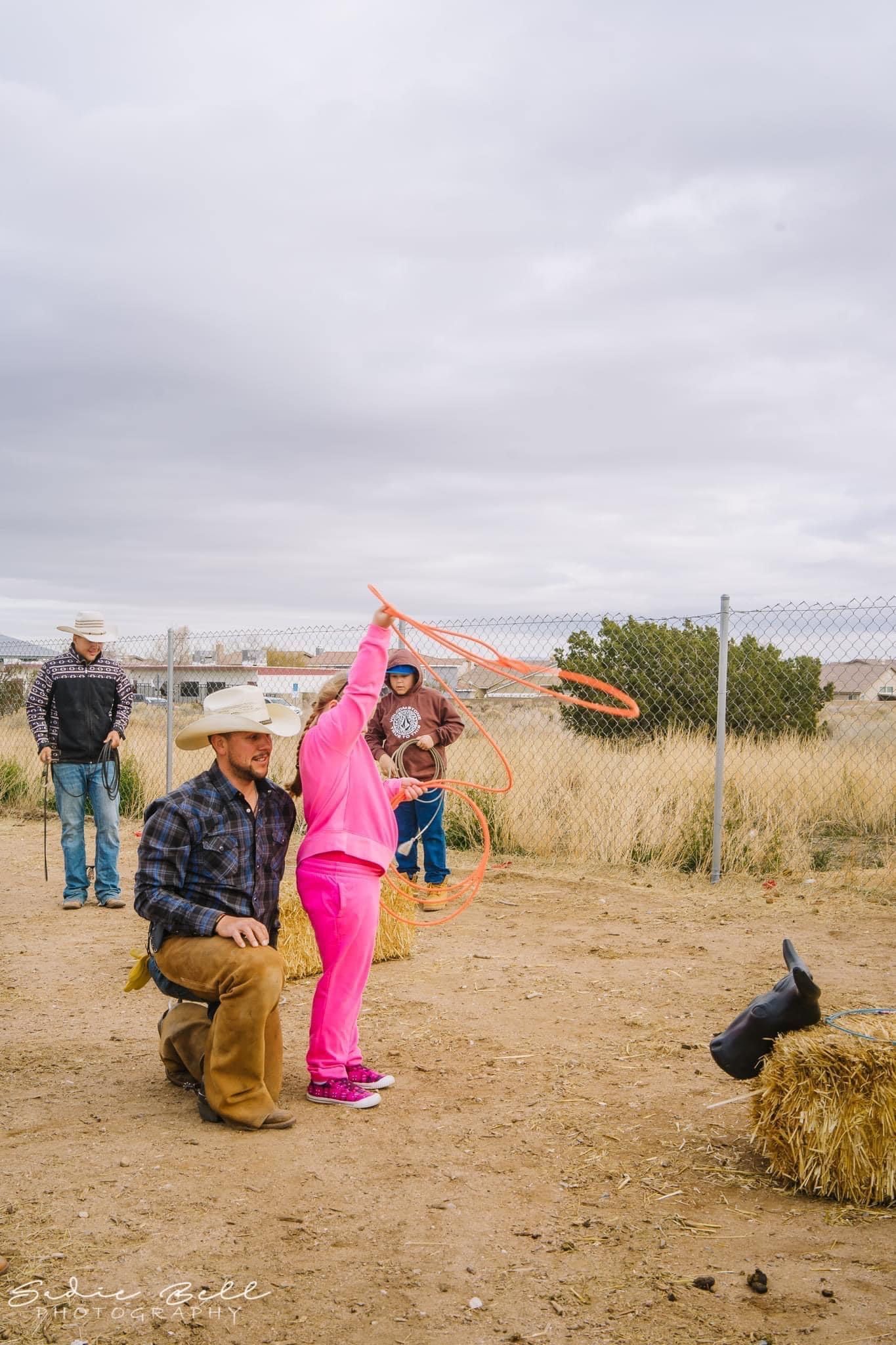A man and a little girl are playing with a lasso in a field.