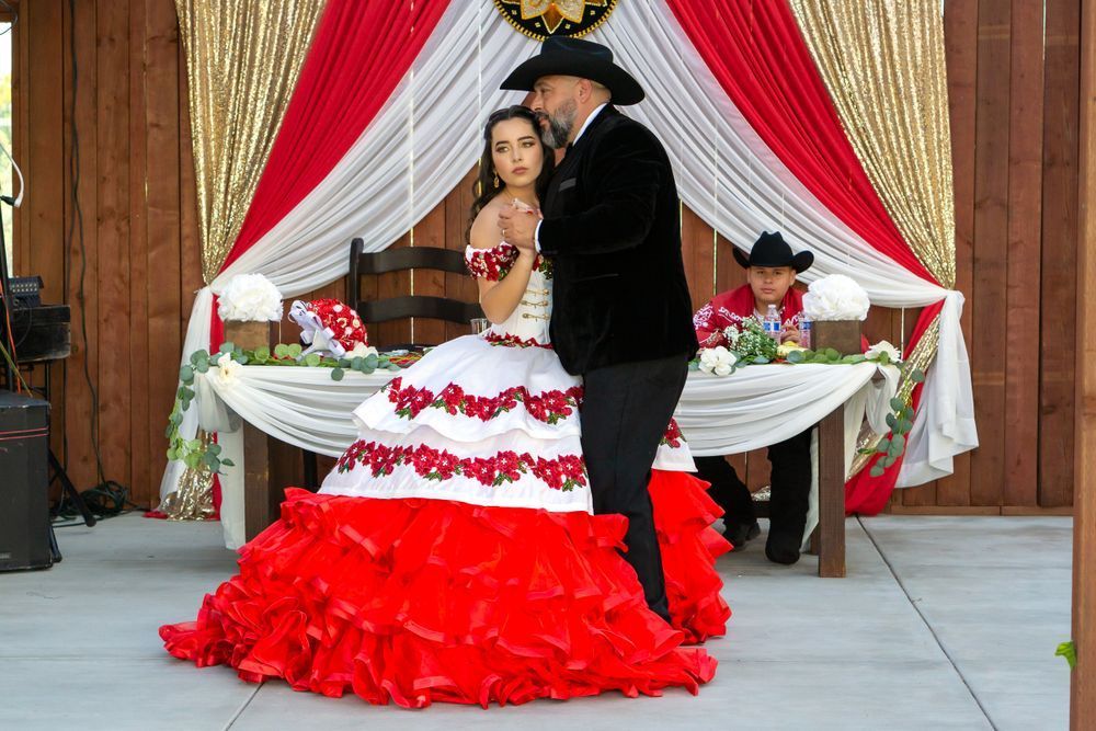 A man in a cowboy hat is kissing a woman in a red and white dress.