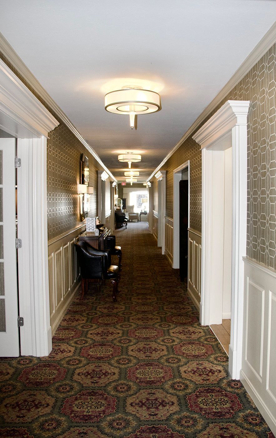 A long hallway with a carpeted floor and a ceiling light