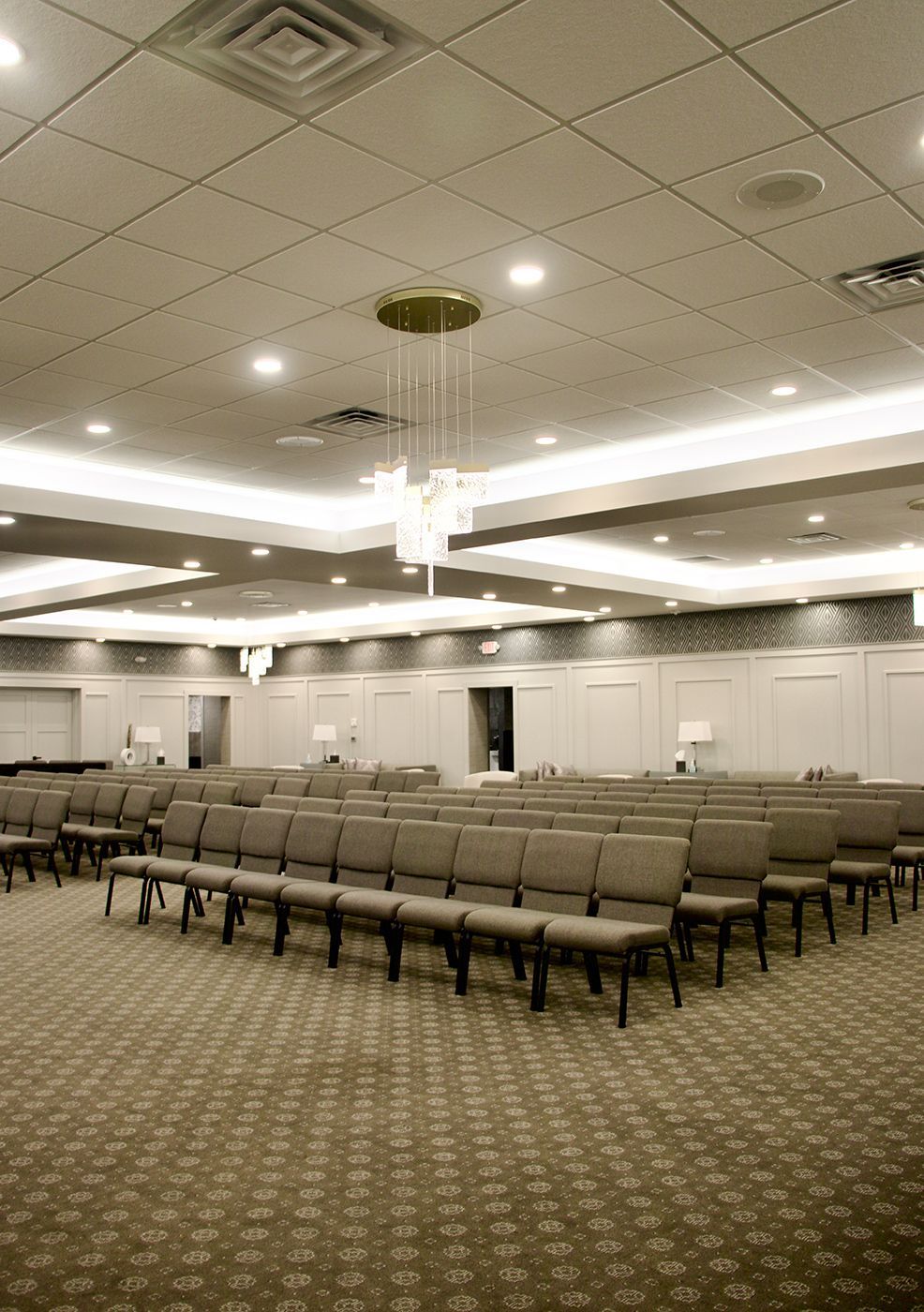 A large room with rows of chairs and a chandelier hanging from the ceiling.