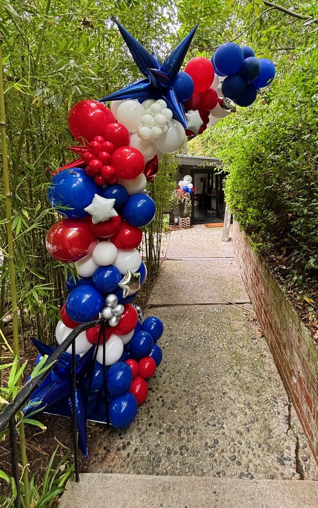 Red, white and blue balloon half arch framing the base of a staircase where guests entered the Fourth of July party