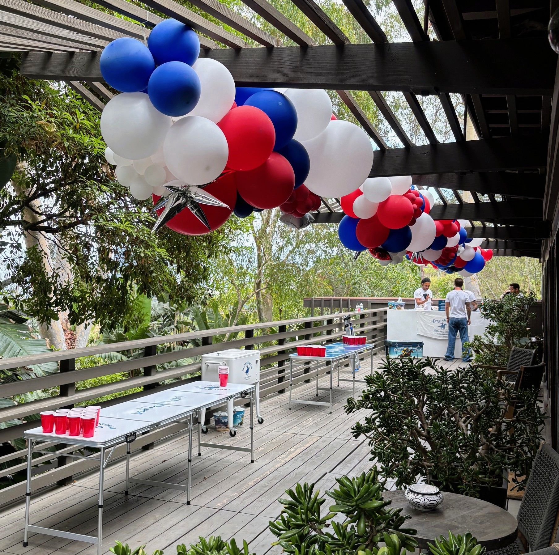 Red, white and blue organic balloon garlands along a patio overhang and above the Crazy Mountain sponsored bar