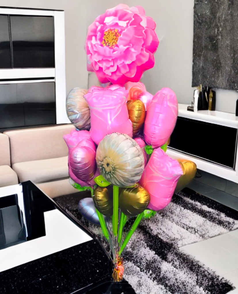 Bouquet of pink and gold foil balloons, including a large peony shape, in a room with a rug and sofa.