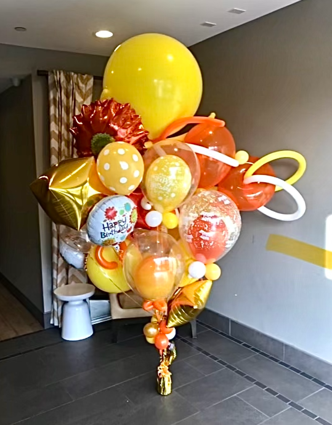 Colorful birthday balloon bouquet in front of a neutral-colored wall.