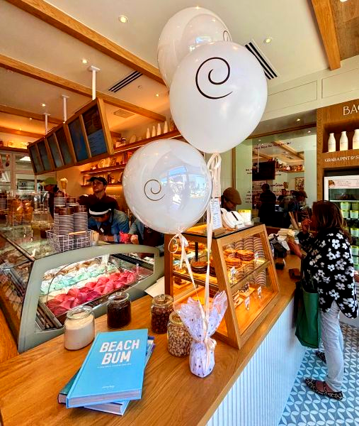 Branded balloon bouquet on the counter inside Bacio di Latte Manhattan Beach as staff scoop gelato for customers