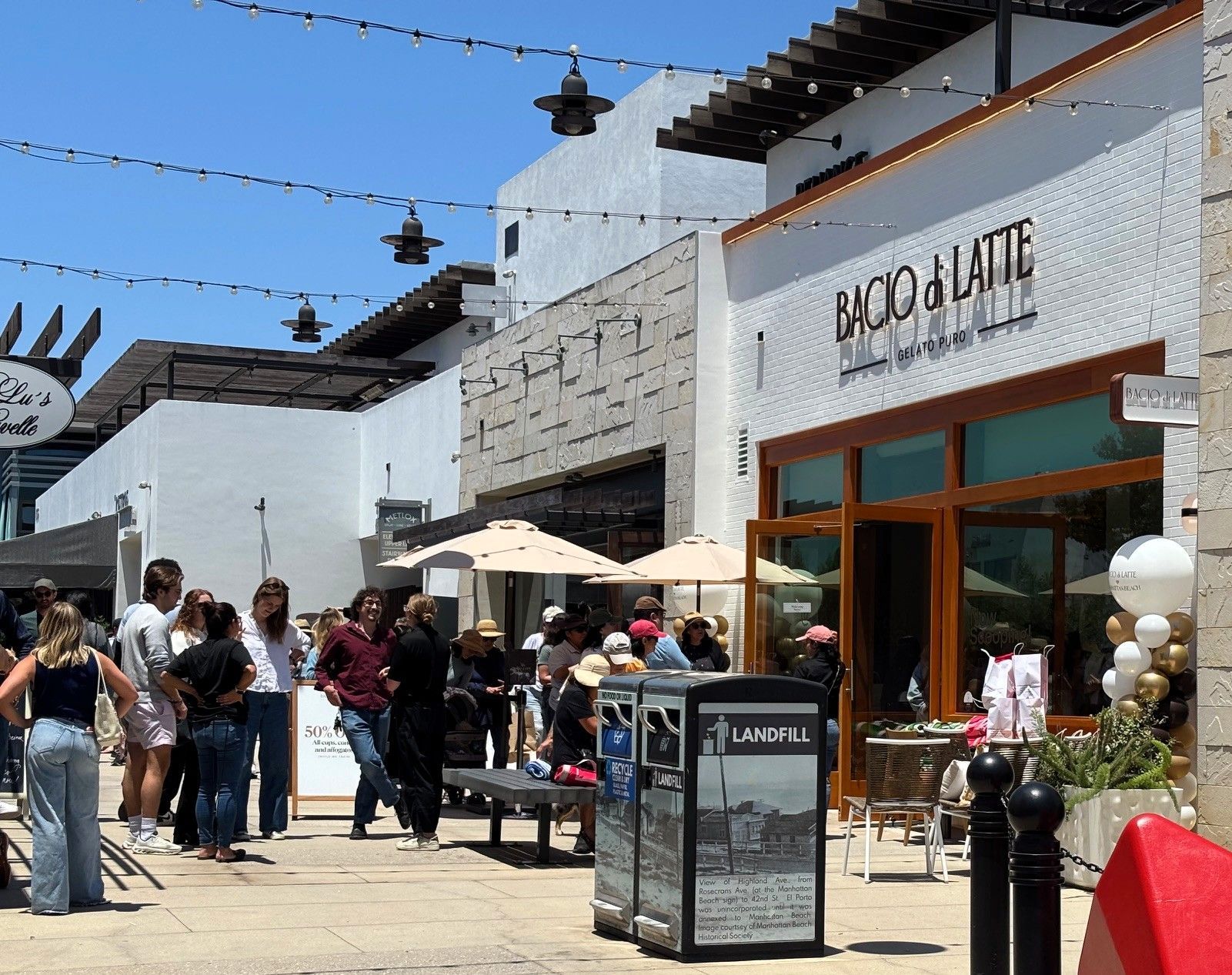 Wide view of the Bacio di Latte Manhattan Beach grand opening with branded balloon columns and a crowd of customers
