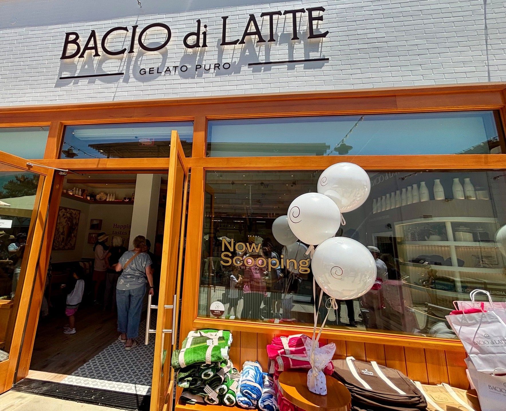 Luxury white branded balloon bouquet with double-bubble balloons and Bacio di Latte logos outside the Manhattan Beach store with customers in line