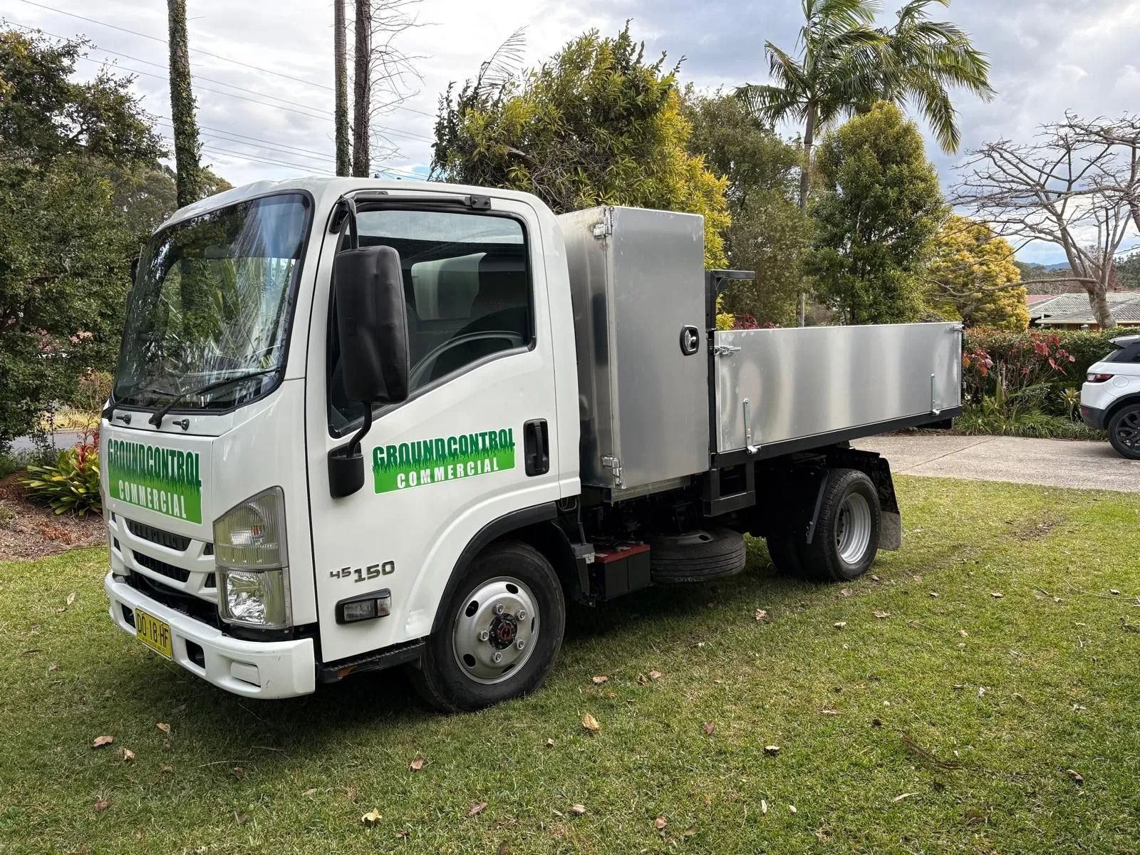 Person Using a String Trimmer to Cut Tall Green Grass — Ground Control Property Maintenance In North Boambee Valley, NSW