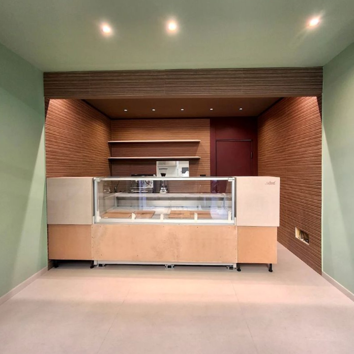 Bancone della reception vuoto in una piccola hall rivestita di mattoni con pareti verde menta e faretti a incasso.