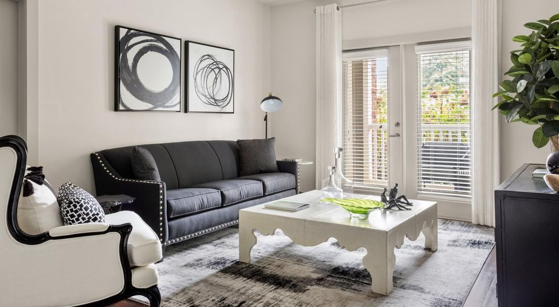 A living room with a black couch and a white coffee table.