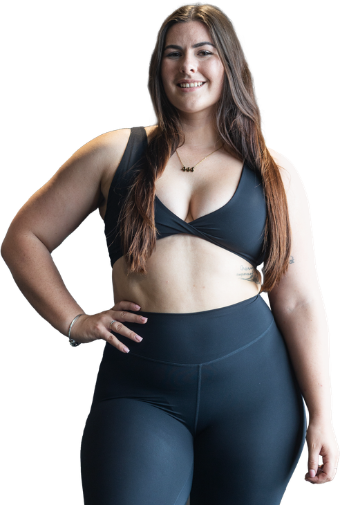 A woman in a black bra and leggings is standing with her hands on her hips. StrongHer by Kyla Fraser - Personalised workout and meal plans