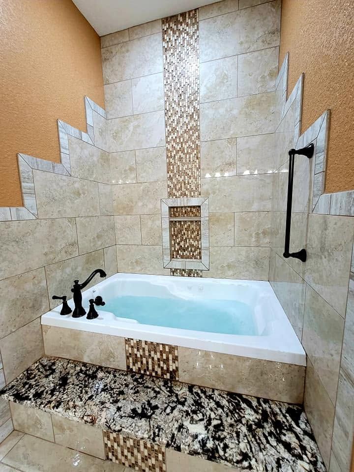 Small bathroom with a freestanding tub, beige tiled walls, and a granite ledge.