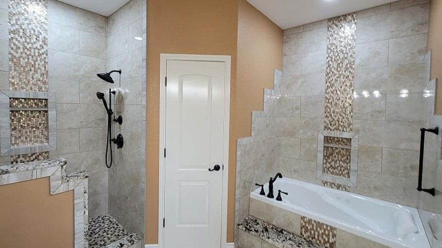 Bathroom with beige tile walls, glass shower, white door, and a bathtub with black fixtures.