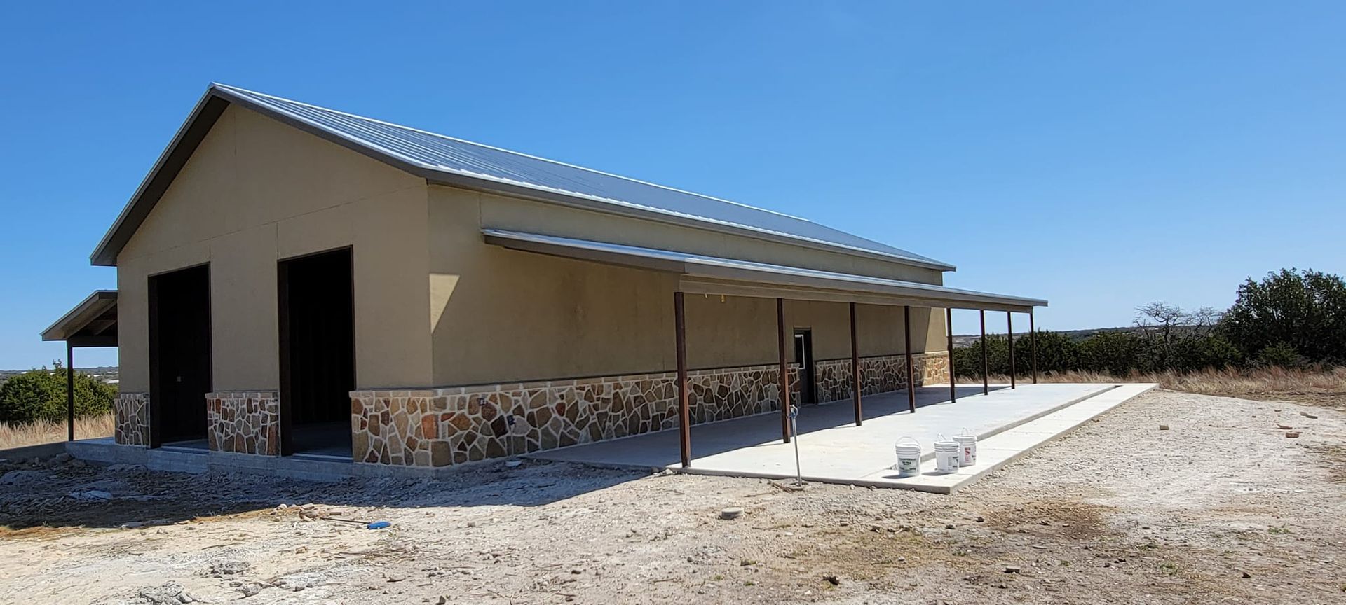 Single-story tan building with a metal roof and covered walkway in a dry, open landscape.