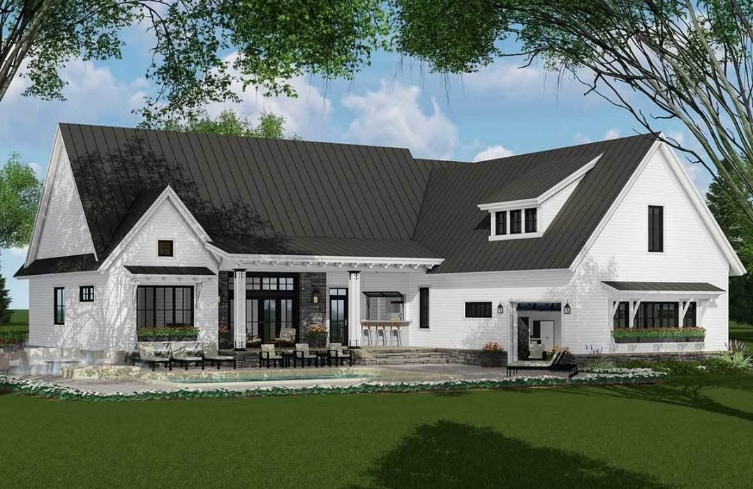 Modern white house with black roof, large windows, and landscaped lawn under a blue sky