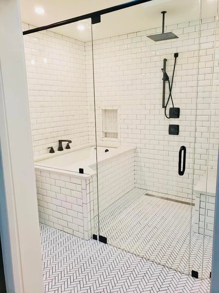 White tiled accessible bathroom with walk-in shower, grab bars, built-in seat, and handheld showerhead