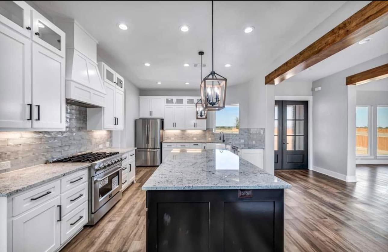 Bright modern kitchen with white cabinets, granite island, stainless appliances, and hardwood floors