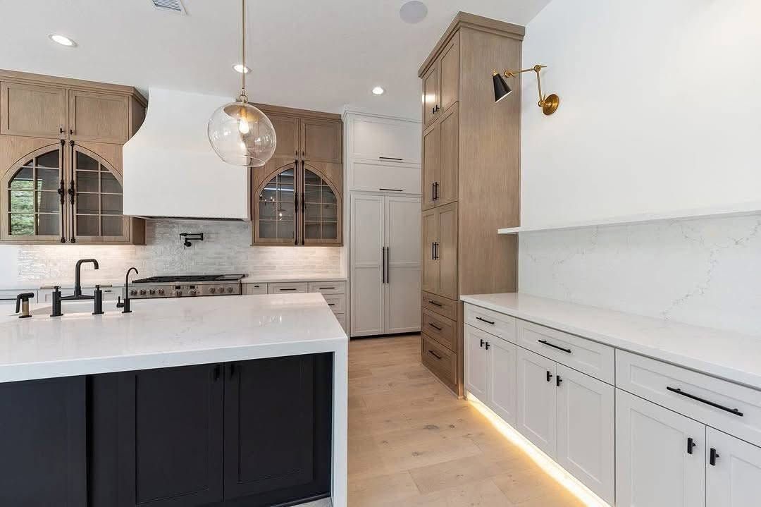 Modern kitchen with white cabinets, black island, wood floors, and pendant lighting