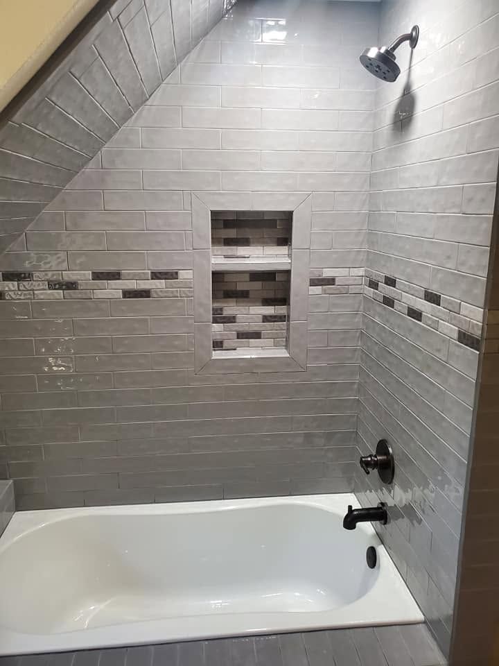 Gray tiled shower-tub combo with built-in niche and a showerhead above the bathtub