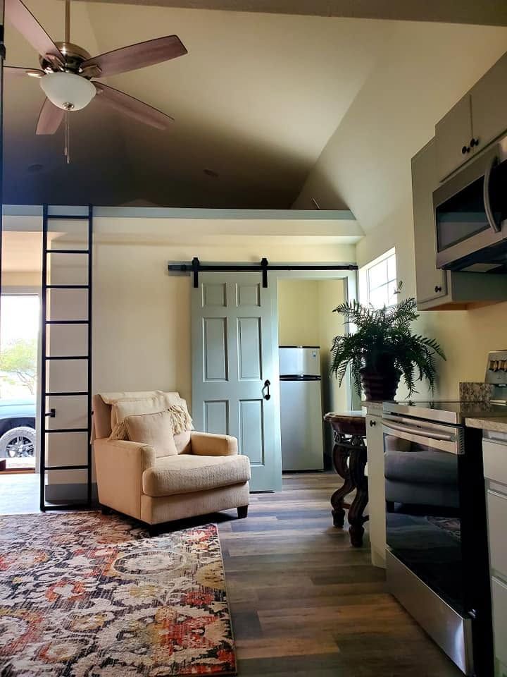 Bright living room with beige armchair, blue sliding door, fireplace, ceiling fan, and patterned rug
