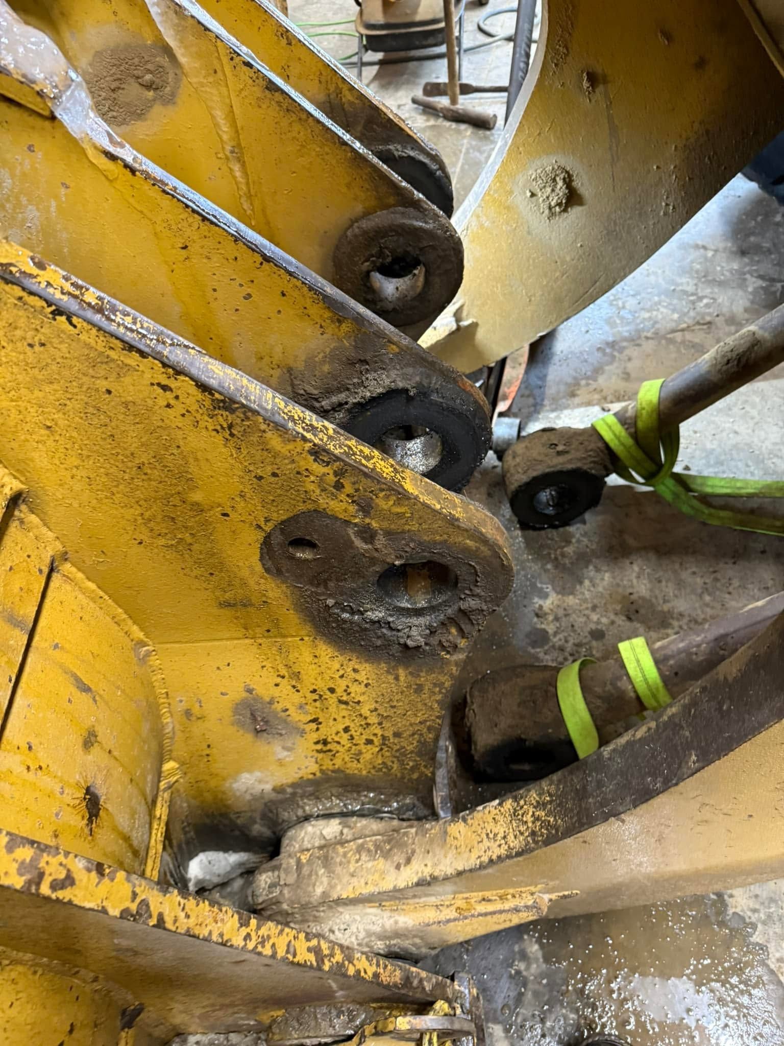 Worker’s gloved hands repairing a yellow heavy machine with worn metal parts | 814 Truck & Equipment Services LLC