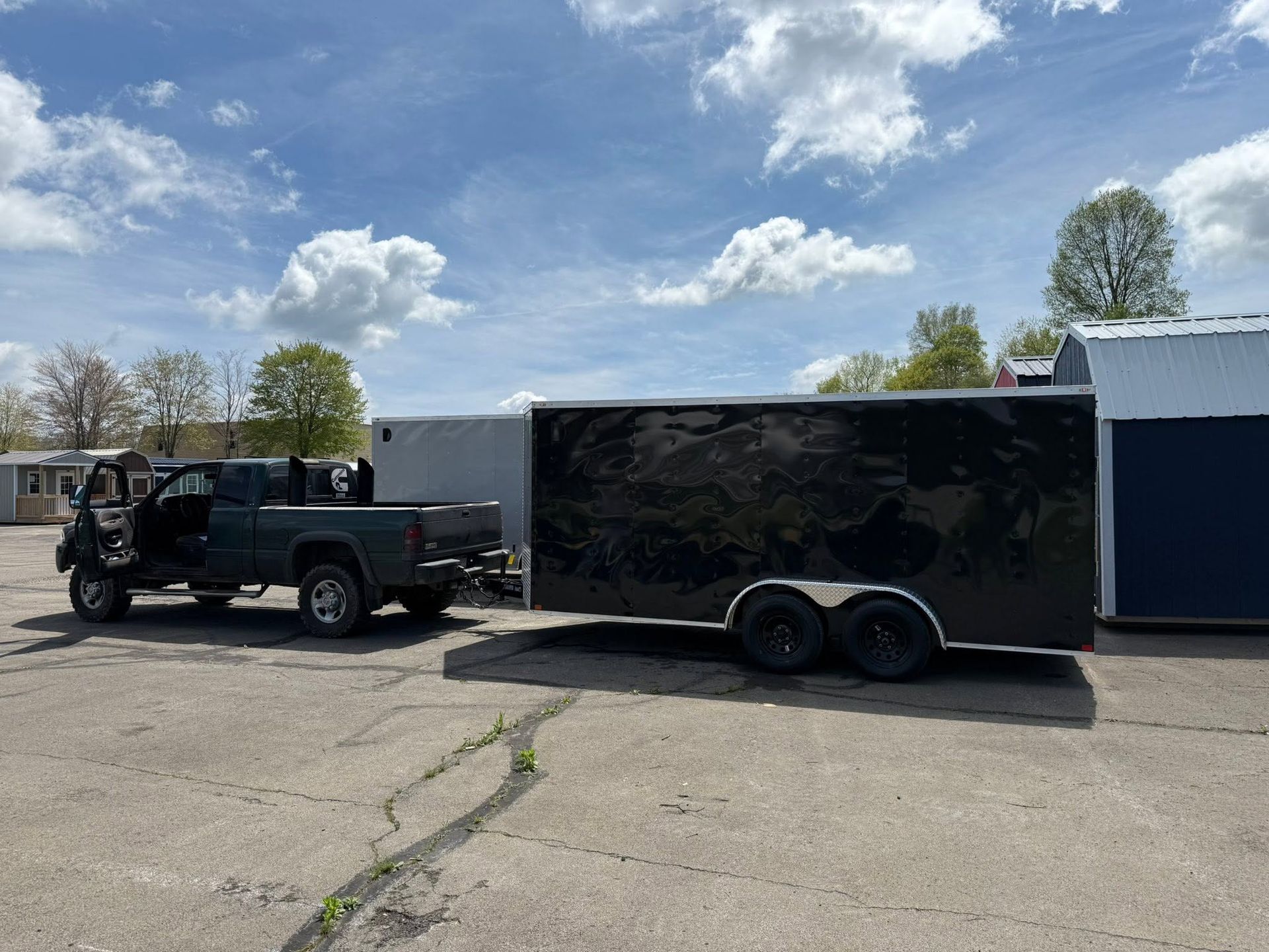Pickup truck towing a black enclosed trailer in a parking lot under a partly cloudy sky | 814 Truck & Equipment Services LLC