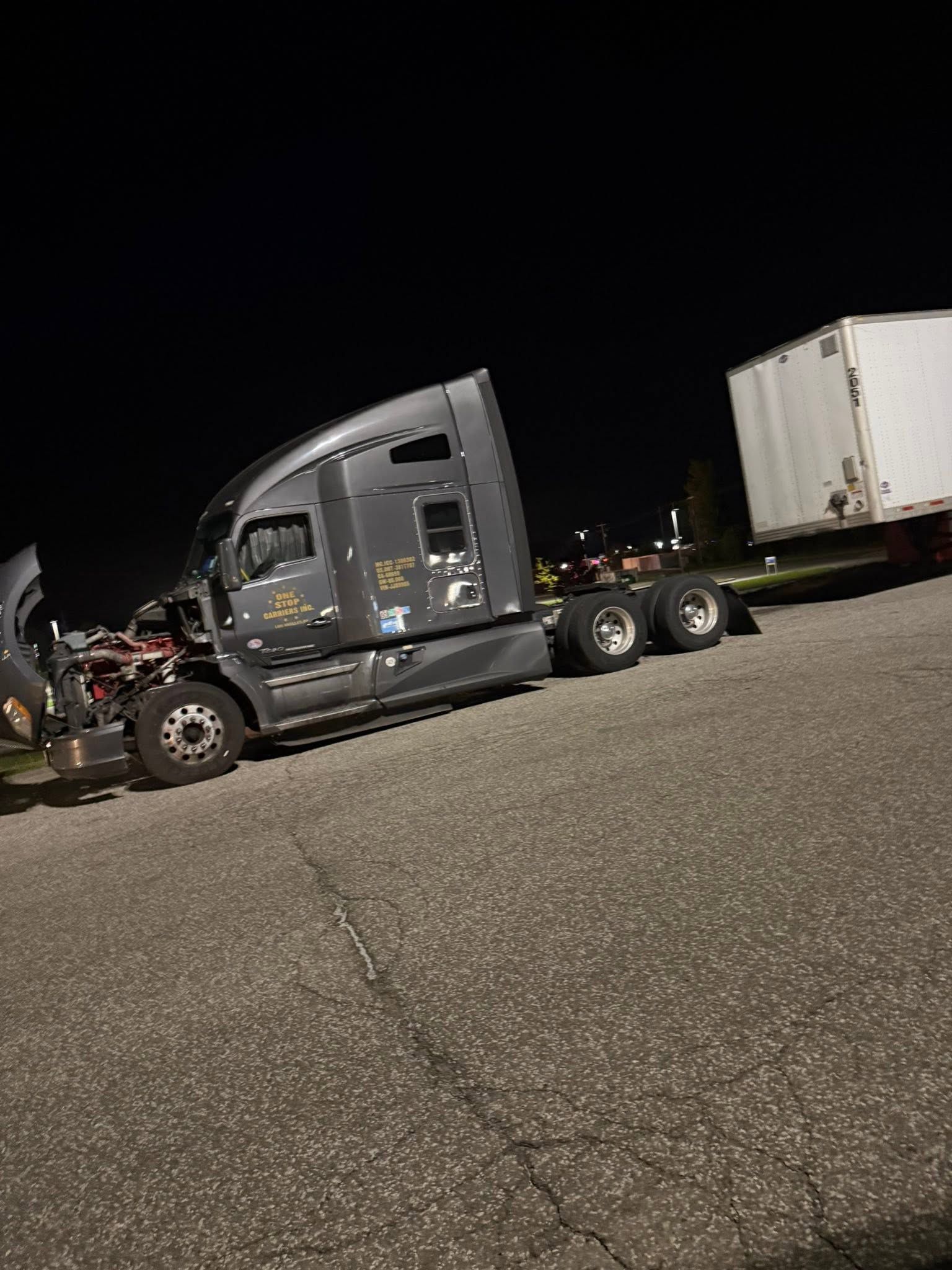 Damaged gray semi-truck with trailer parked at night in a gravel lot after a crash | 814 Truck & Equipment Services LLC