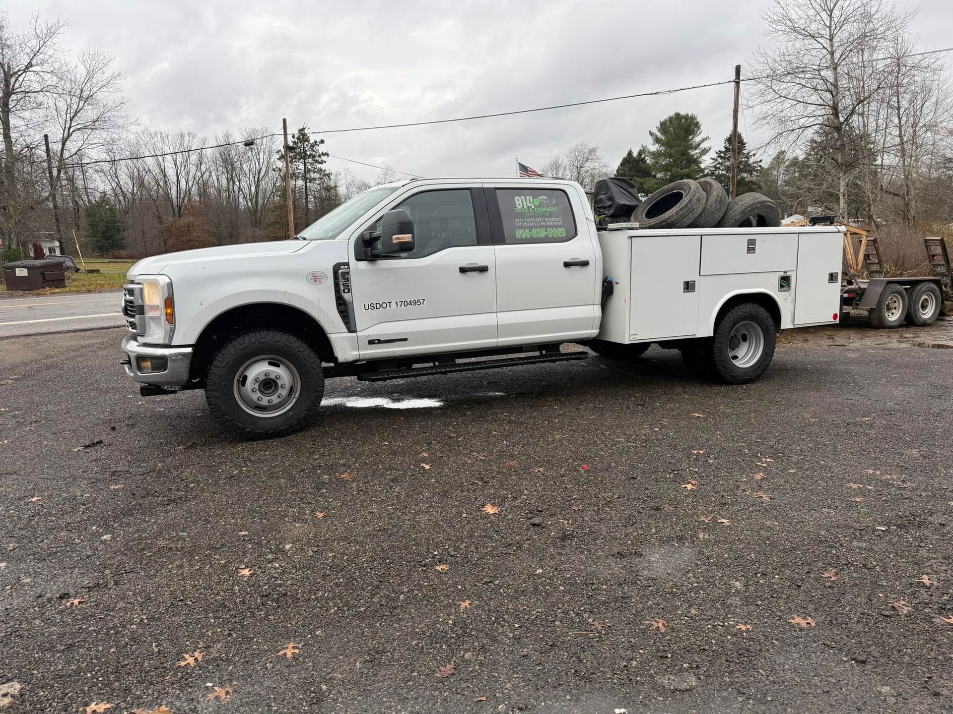 White utility pickup truck parked on gravel in a rural yard, with trees and equipment in the background | 814 Truck & Equipment Services LLC