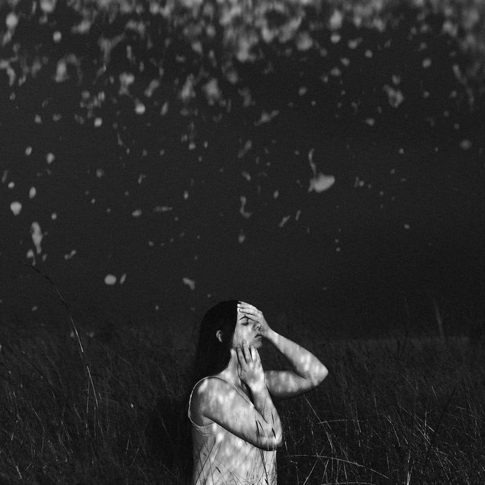 A black and white photo of a woman standing in a field