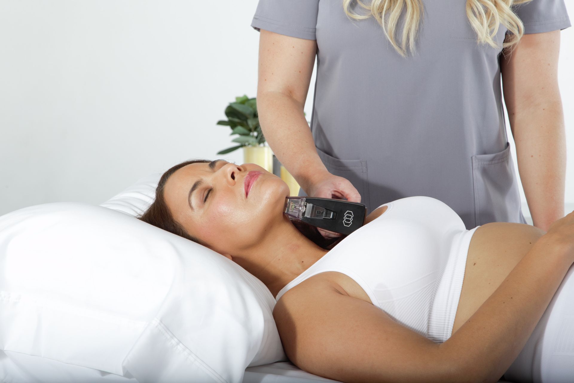Person receiving microneedling treatment with black device on face. Blue gloves, white cloth, setting indoors.